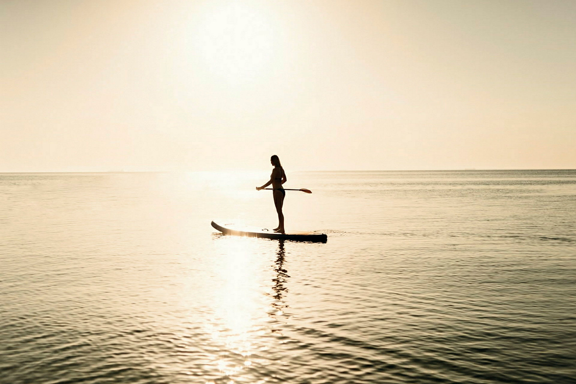 Person som paddlar på en stand-up paddleboard i solnedgång. (AI-genererad text)