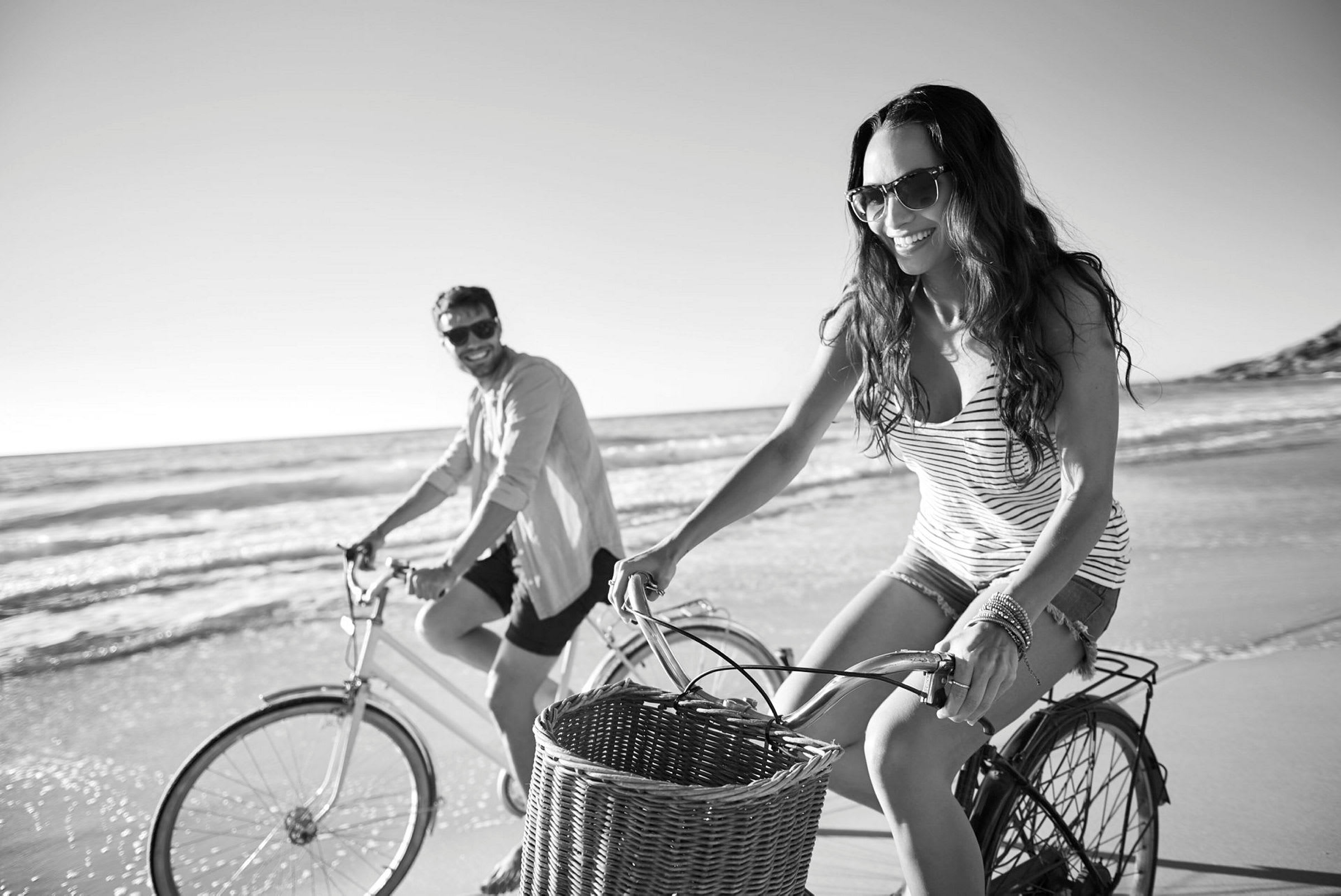 Två personer cyklar längs en strand. (AI-genererad text)