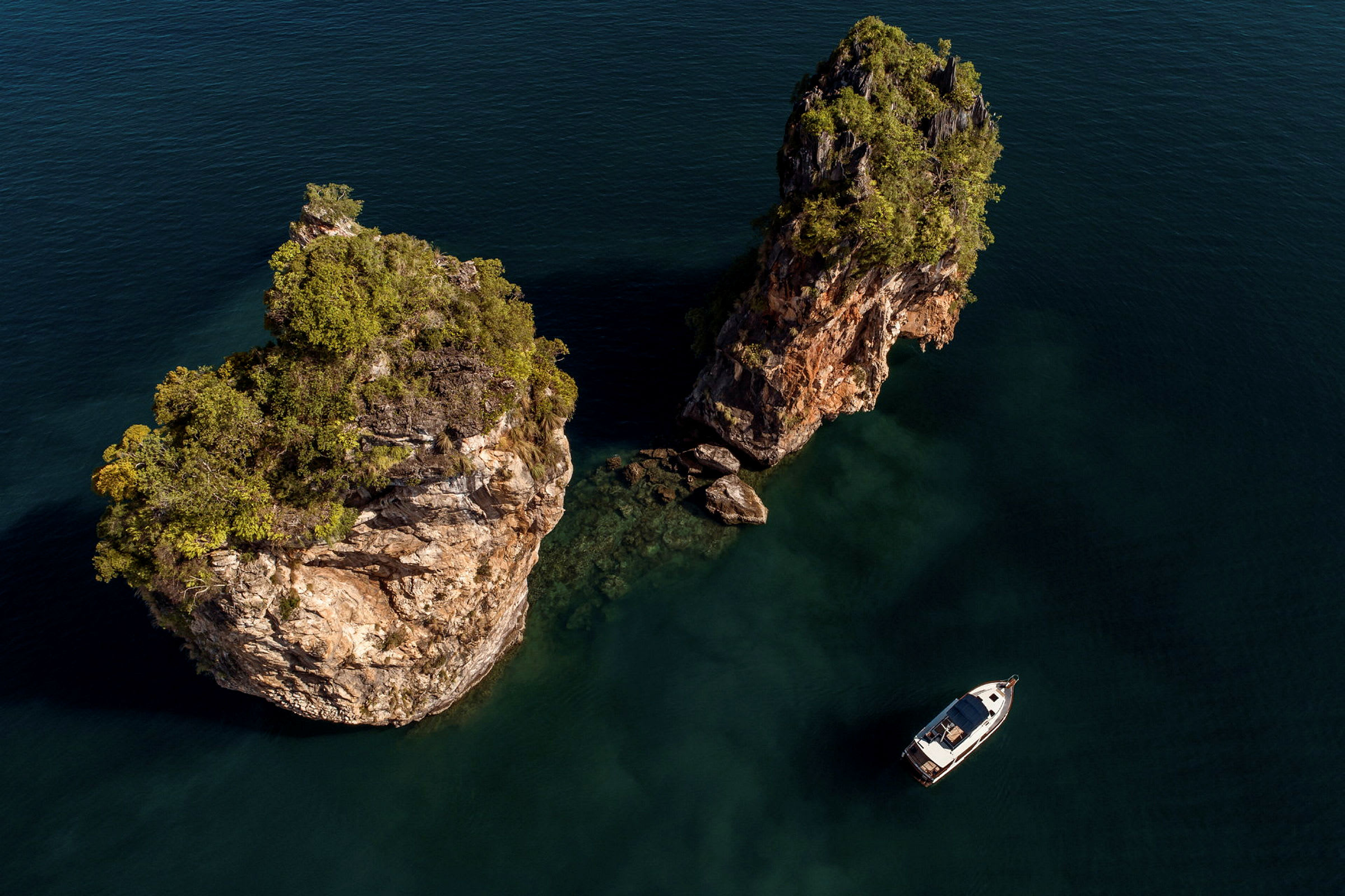 En båt ligger vid två klippformationer i havet. (AI-genererad text)