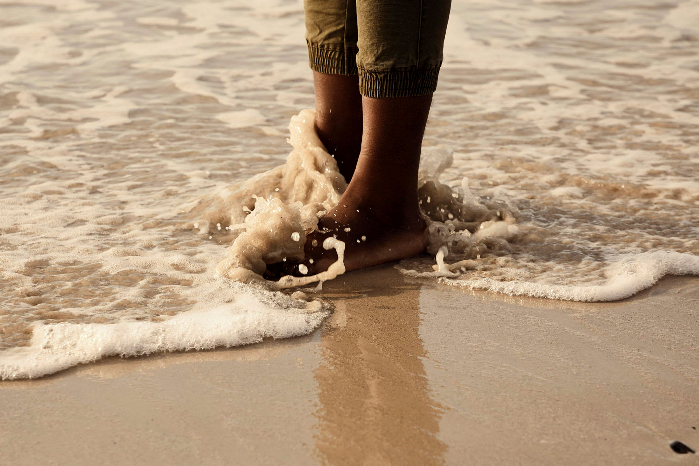 Person står med fötterna i vatten vid strandkanten. (AI-genererad text)