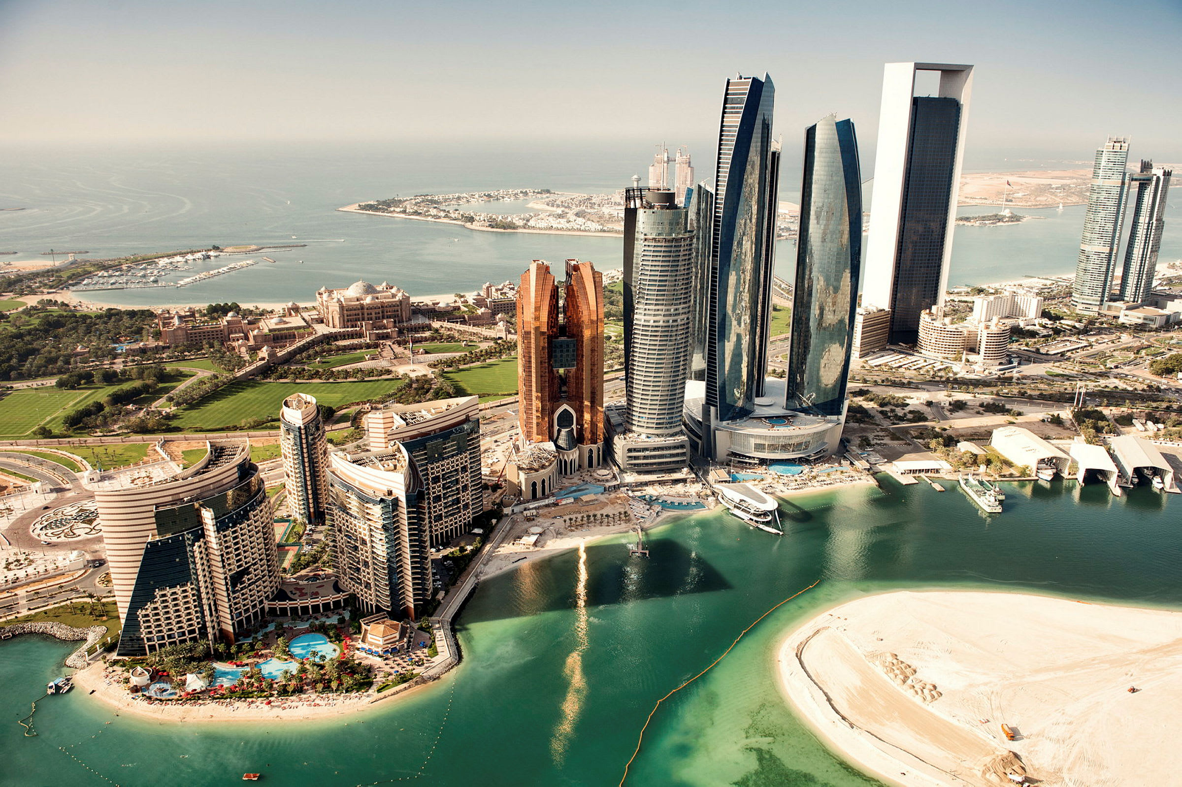 Flygfoto av Abu Dhabi med moderna skyskrapor, en sandstrand och den omgivande kusten. (AI-genererad text)