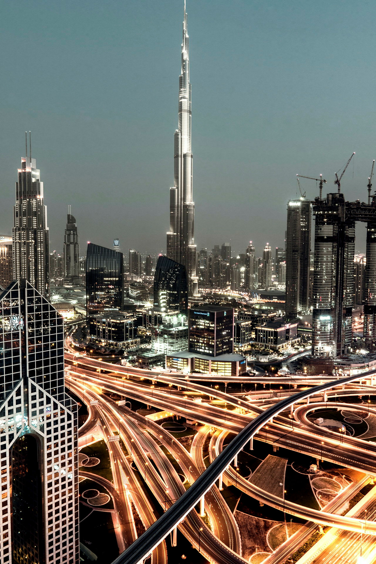 En stadsbild med höga skyskrapor, inklusive Burj Khalifa, med ljusstarka motorvägar i förgrunden. (AI-genererad text)