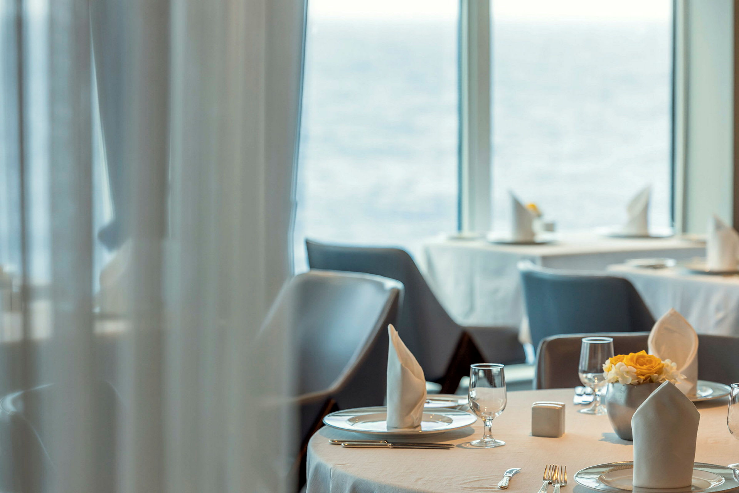 Ett dukat bord i en restaurang med utsikt över havet. (AI-genererad text)