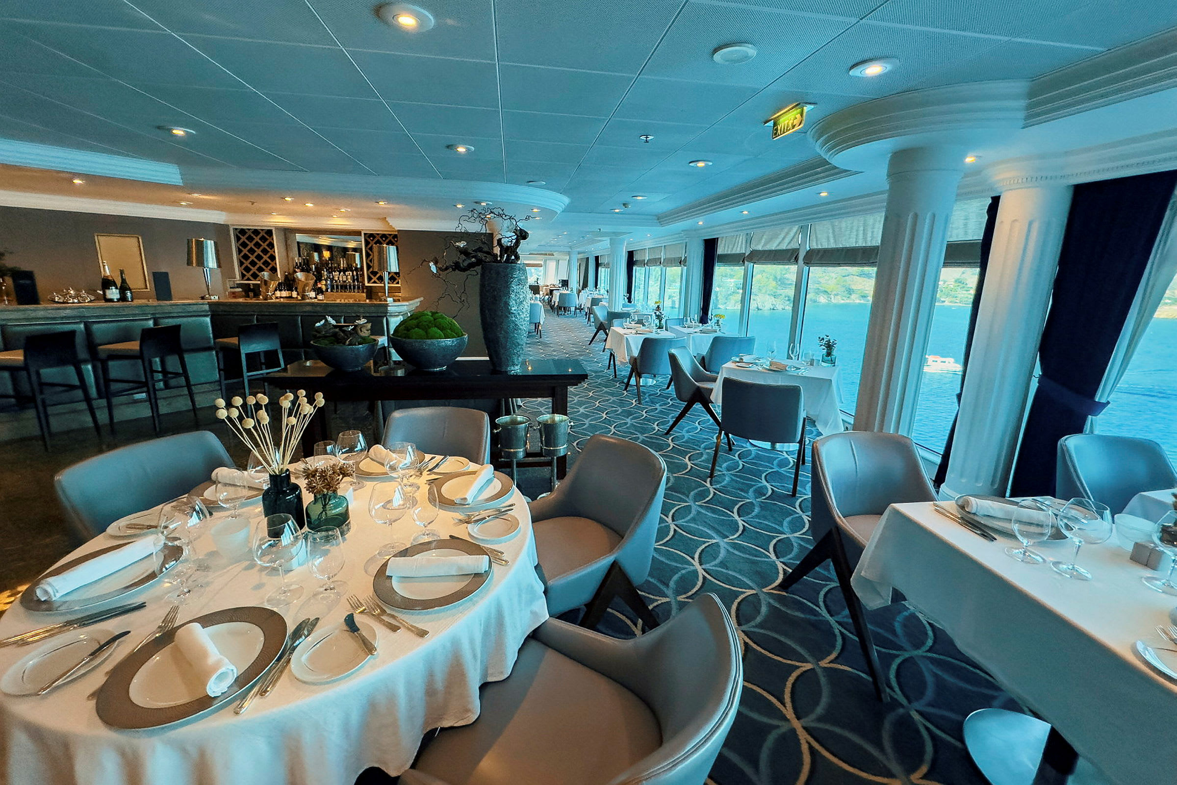 Restaurang med dukade bord, stora fönster och havsutsikt. (AI-genererad text)