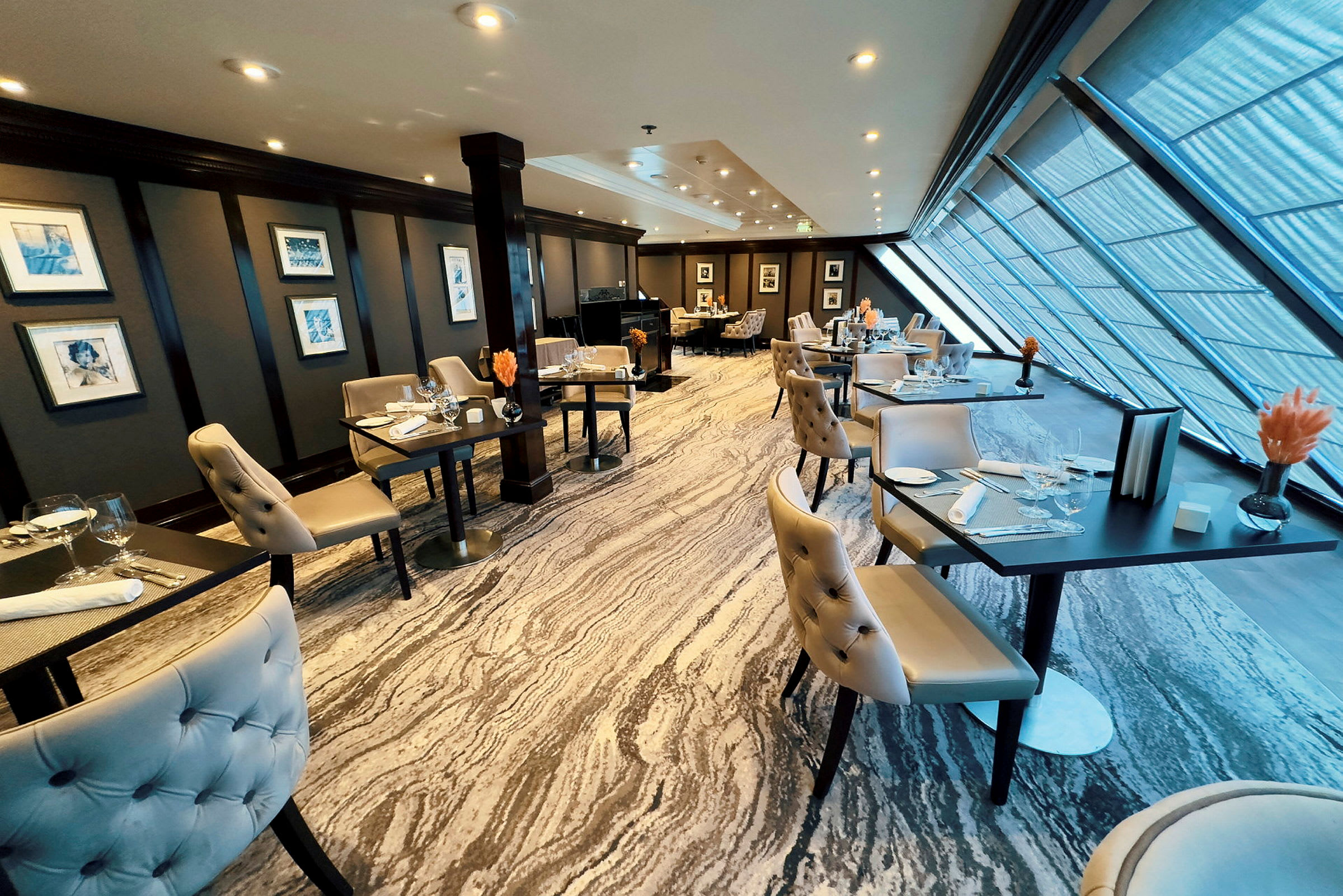 Restaurang med elegant inredning, bord och stolar samt stora fönster. (AI-genererad text)