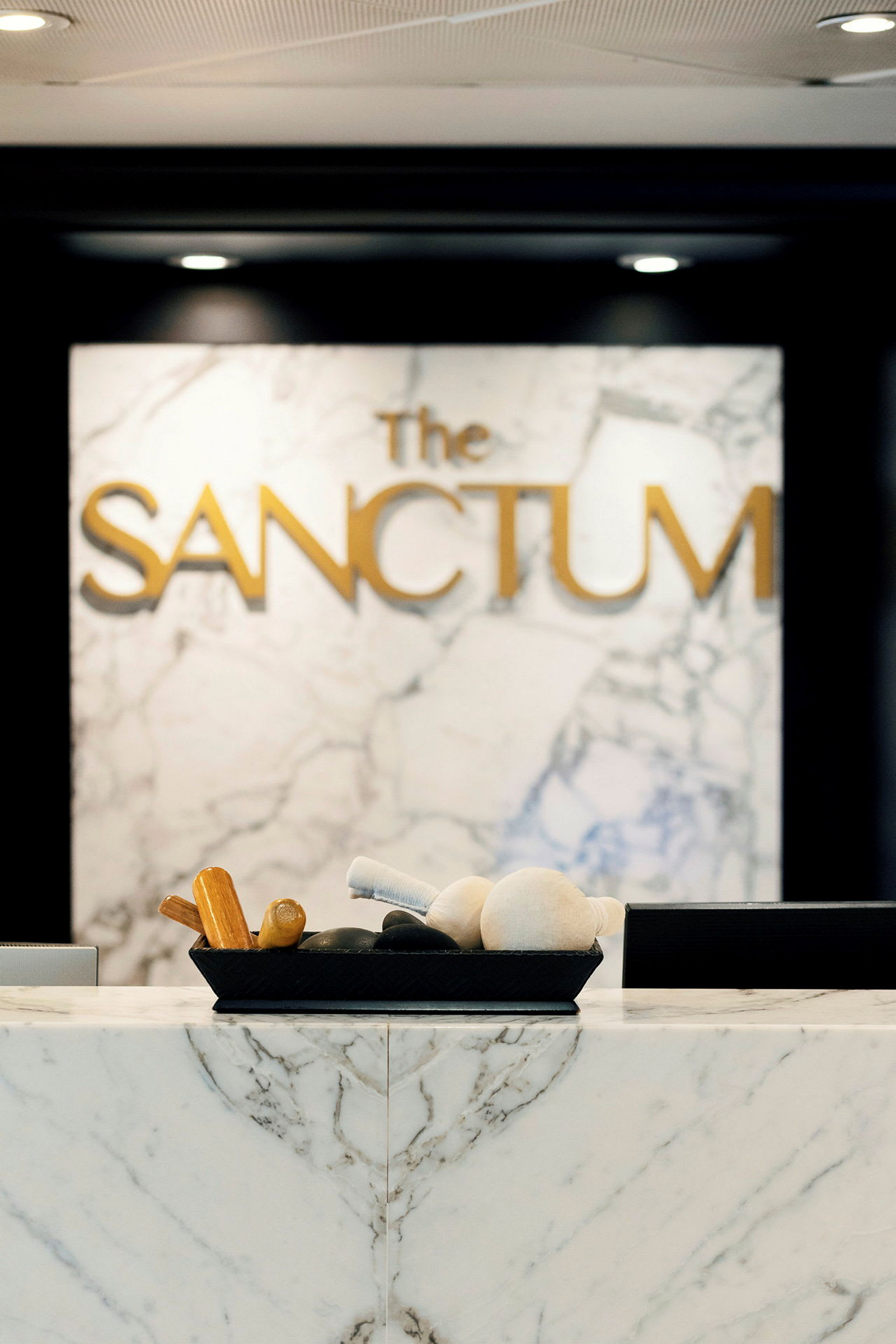 Bild av en bänkskiva i marmor med massageverktyg i en skål, bakom en bakgrund med texten 'The Sanctum'. (AI-genererad text)